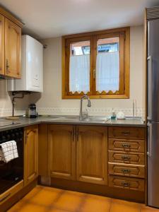 uma cozinha com armários de madeira e um frigorífico de aço inoxidável em Casa Martagón - kasasbenas em Benasque