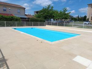 a large blue swimming pool in a yard at Le cocon de Marie,piscine, balcon, parking gratuit, baignoire in Carcassonne