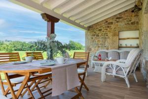 un patio con mesa de madera, sillas y pared de piedra. en Villa Colasa, casa rústica con encanto en Selaya, en Selaya