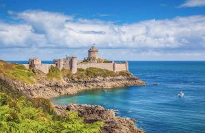 a castle sitting on top of a cliff next to the ocean at À 2mn de la plage, maison avec grand terrain clos in Plérin