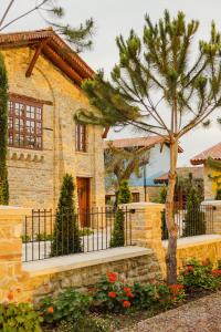 a stone house with a fence and a tree at Blerina's Agritourism Concept in Laknas