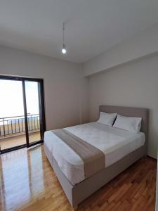 a white bedroom with a bed and a large window at Watch Penthouse City Center & parking in Chania