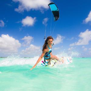 una mujer montando una ola en una tabla de surf en el océano en La Smeraldina Resort en Santa Teresa Gallura