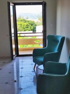 two green chairs in a room with a large window at Watch Penthouse City Center & parking in Chania Town