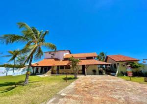 une maison avec un palmier en face dans l'établissement Mansão do Kite - Praia do Coqueiro, à Luis Correia