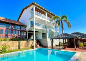 una casa con piscina frente a un edificio en Mansão do Kite - Praia do Coqueiro, en Luís Correia