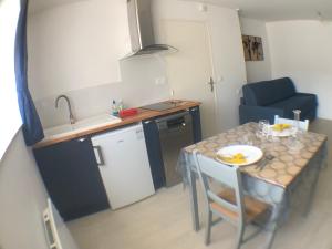 une petite cuisine avec une table et un canapé bleu dans l'établissement Les studios de Philibert, à Figeac