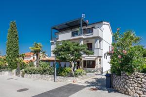 a white house with trees and bushes at Apartment Rukavina in Njivice