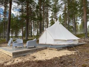 a tent with two chairs and a table in the woods at Osensjøen Camping in Valmen