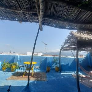 a patio with a table and chairs and a blue wall at Riad Khmisa in Tetouan