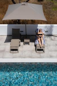 una donna seduta su una sedia accanto alla piscina di Ria Formosa Guest House a Faro