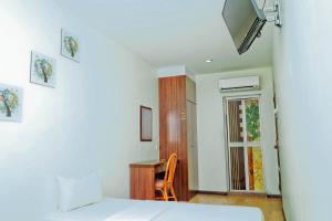 a room with two beds and a desk and a window at Rimaniz Hotel Alor Setar in Alor Setar