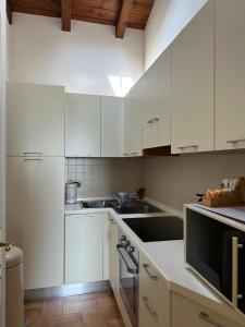 uma cozinha branca com armários brancos e um lavatório em Vittoria Apartment em Serravalle Scrivia