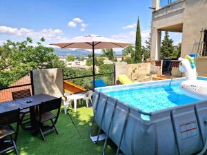 a swimming pool with a table and an umbrella at Villa Marseille dans les hauteurs in Marseille