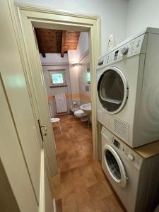 a washer and dryer in a bathroom with a toilet at Vittoria Apartment in Serravalle Scrivia