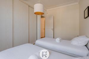 two beds in a room with white walls at R'Apparts T3 Bastille Horizon in Grenoble