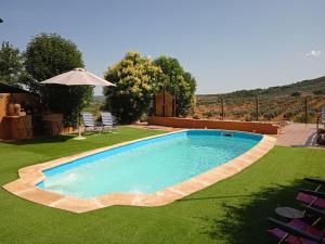 a swimming pool in a yard with chairs and an umbrella at La Tierra Verde STUDIO in Alcuéscar