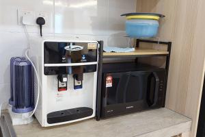 a small kitchen with a microwave and a refrigerator at Sunsky Condominium Homestay 2 in Miri