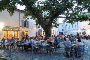 Les Pertuis Rochelais في Périgny: مجموعة من الناس يجلسون على الطاولات تحت شجرة