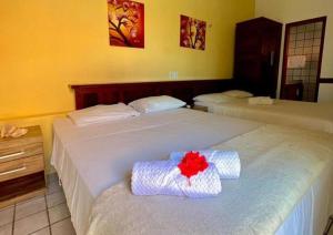 Dos camas en una habitación de hotel con una flor roja. en Mansão do Kite - Praia do Coqueiro, en Luís Correia