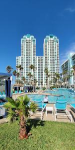 a pool with chairs and a palm tree and buildings at Sapphire 1706 in South Padre Island