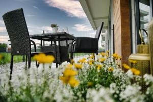 a patio with a table and chairs and flowers at ApartPark Centrum Zator Bronze in Zator