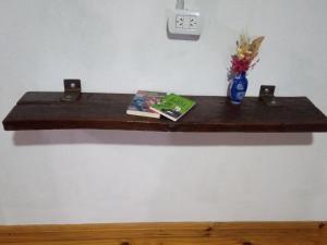 a shelf on a wall with a book and a vase of flowers at Lo de la Abuela in Goya