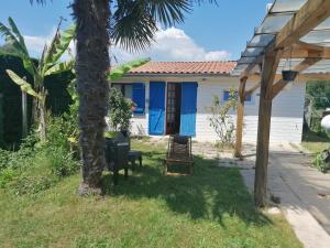 Saint-Vivien-de-MédocMaisonnette de charme entre plages et estuaire的一座带蓝色门和棕榈树的房子