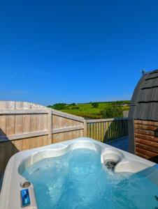 a hot tub in a backyard with a wooden fence at Pond View Pod 2 with Private Hot Tub - Fife - Loch Leven - Lomond Hills in Kelty