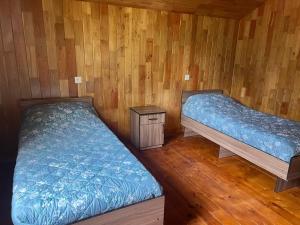 two beds in a room with wooden walls and wood floors at Lakeside Villa Issyk Kul in Cholpon-Ata