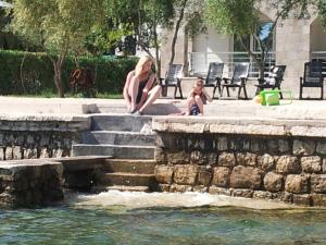 a woman and a child sitting on steps next to a fountain at Apartments Villa Danilovic in Herceg-Novi