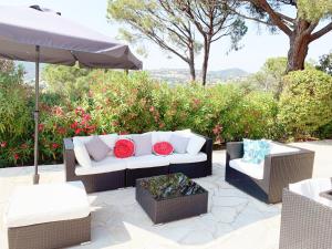 eine Couch und zwei Stühle und ein Regenschirm auf einer Terrasse in der Unterkunft Villa avec piscine privée in Sainte-Maxime