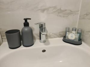 a sink with a bottle of soap and other items on it at Homestay by BIC Oates 4 in Dewsbury