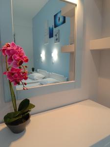 un jarrón con una flor en una mesa frente a un espejo en ΑΥΡΑ Ενοικιαζόμενα Δωμάτια - AVRA Rooms To Let, en Galissas