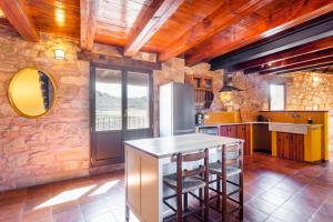 a kitchen with a stone wall and a table with stools at RUSTIKALPUENTE BALDOVAR II in Baldovar