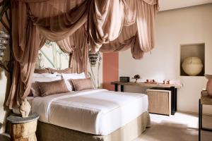 Niove Suites Milos في بلاكا ميلو: غرفة نوم بسرير ابيض مع ستائر