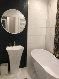 W łazience znajduje się biała wanna, umywalka i lustro. w obiekcie Solankowe Zacisze De Lux Inowrocław w mieście Inowrocław