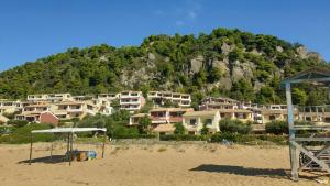 Corfu Glyfada Menigos Resort Home 72 في غليفادا: مجموعة منازل على الشاطئ مع جبل