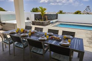 un tavolo con cibo e bevande su un patio con piscina di 205 - Casa Santuario By Villas Now Ltd a Playa Blanca