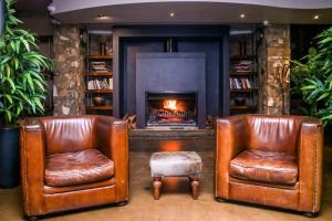 two leather chairs in a living room with a fireplace at Zebula Boutique Hotel in Mabula