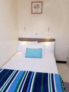 Una cama blanca con una almohada azul encima. en Entire Unit Fully Air-conditioned with Hi-Speed WiFi en Mabalacat