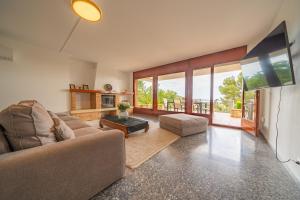 a living room with a couch and a tv at Villa Santa Cristina Lux, Ideal Familias, frente al Mar - Cala Treumal in Blanes