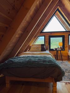 Bett in einem Zimmer mit einem großen Fenster in der Unterkunft Runolist Chalet in Žabljak
