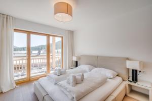 Cama blanca grande en habitación con ventana grande en Chalet Bergliebe zentral mit Bergblick en Seefeld in Tirol