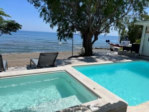 a swimming pool next to a beach with a tree at Nikkon Luxury Living in Arvi