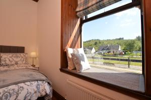 a bedroom with a window with a view of a house at Cairnbaan House in Cairnbaan