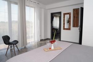 a white room with a table with a vase of flowers and a chair at Pensiunea Grand in Eforie Nord +35 photos