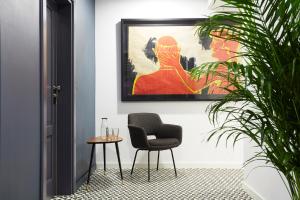 Bez Kantów Art Rooms في وارسو: كرسي وطاولة في غرفة مع لوحة
