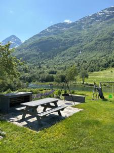 uma mesa de piquenique e baloiços num campo com uma montanha em Naustvoll em Olden