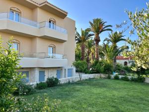 a building with palm trees and a yard at Lili Hotel in Amoudara Herakliou